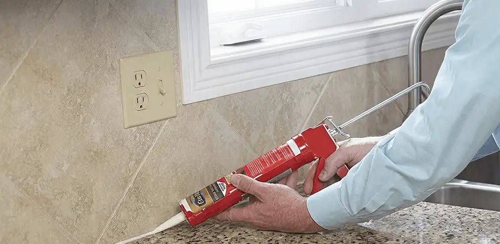 Handyman applying caulk along a kitchen backsplash and countertop seam in Chattanooga, TN