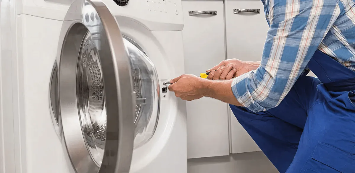 Handyman repairing a clothes dryer and checking electrical connections in Chattanooga, TN