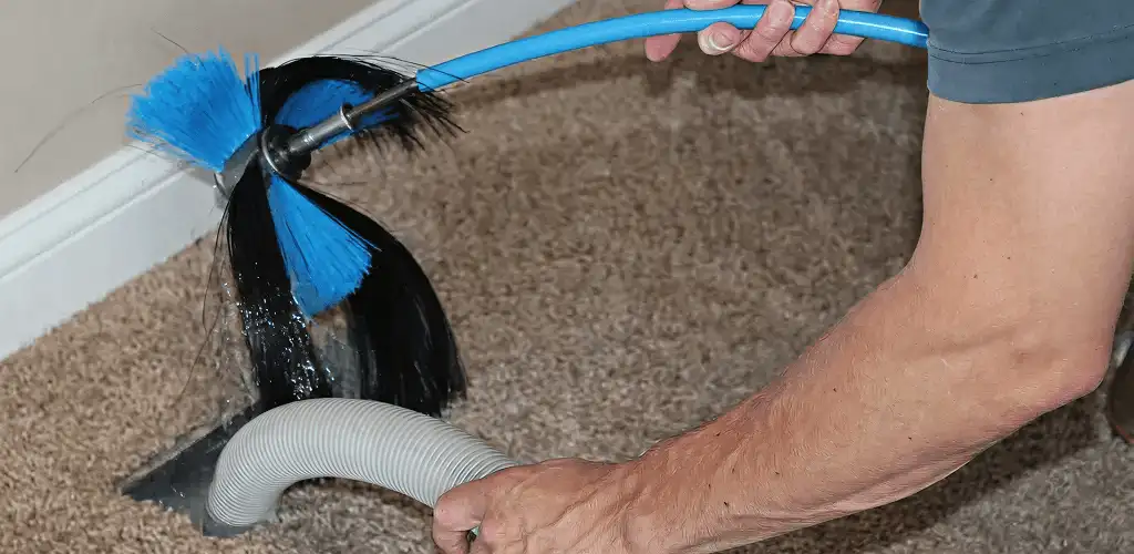 Dryer vent cleaning technician brushing lint from a vent line in Chattanooga, TN