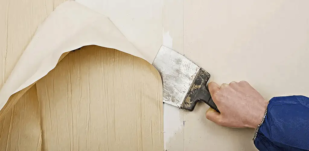 Handyman removing wallpaper with a scraper for wall preparation in Chattanooga, TN
