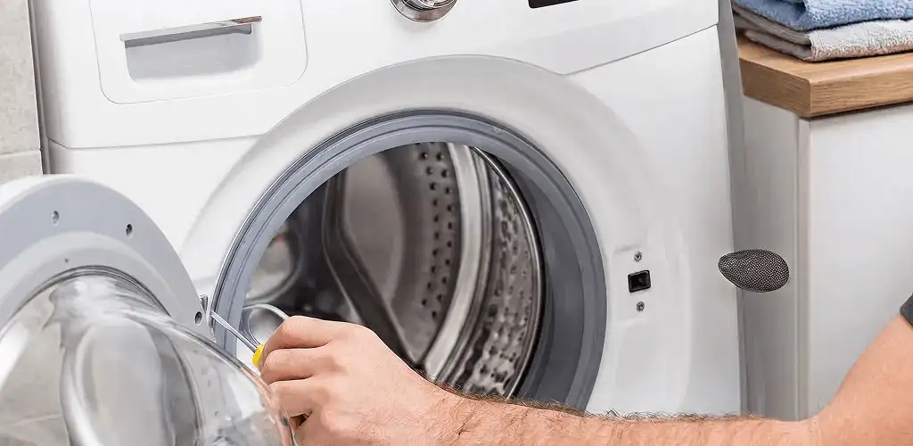 Handyman repairing a front-load washing machine and inspecting the drum in Chattanooga, TN