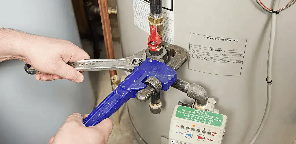 Water heater repair technician tightening the shutoff valve and supply line in Chattanooga, TN
